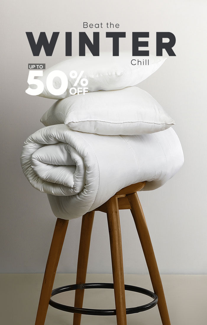 Cozy white bedding on a wooden stool, promoting winter sale with up to 50% off at Home Deco & More