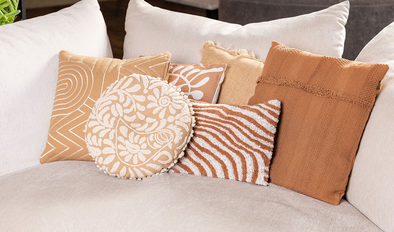 Decorative cushions in beige and terracotta tones styled on a sofa.