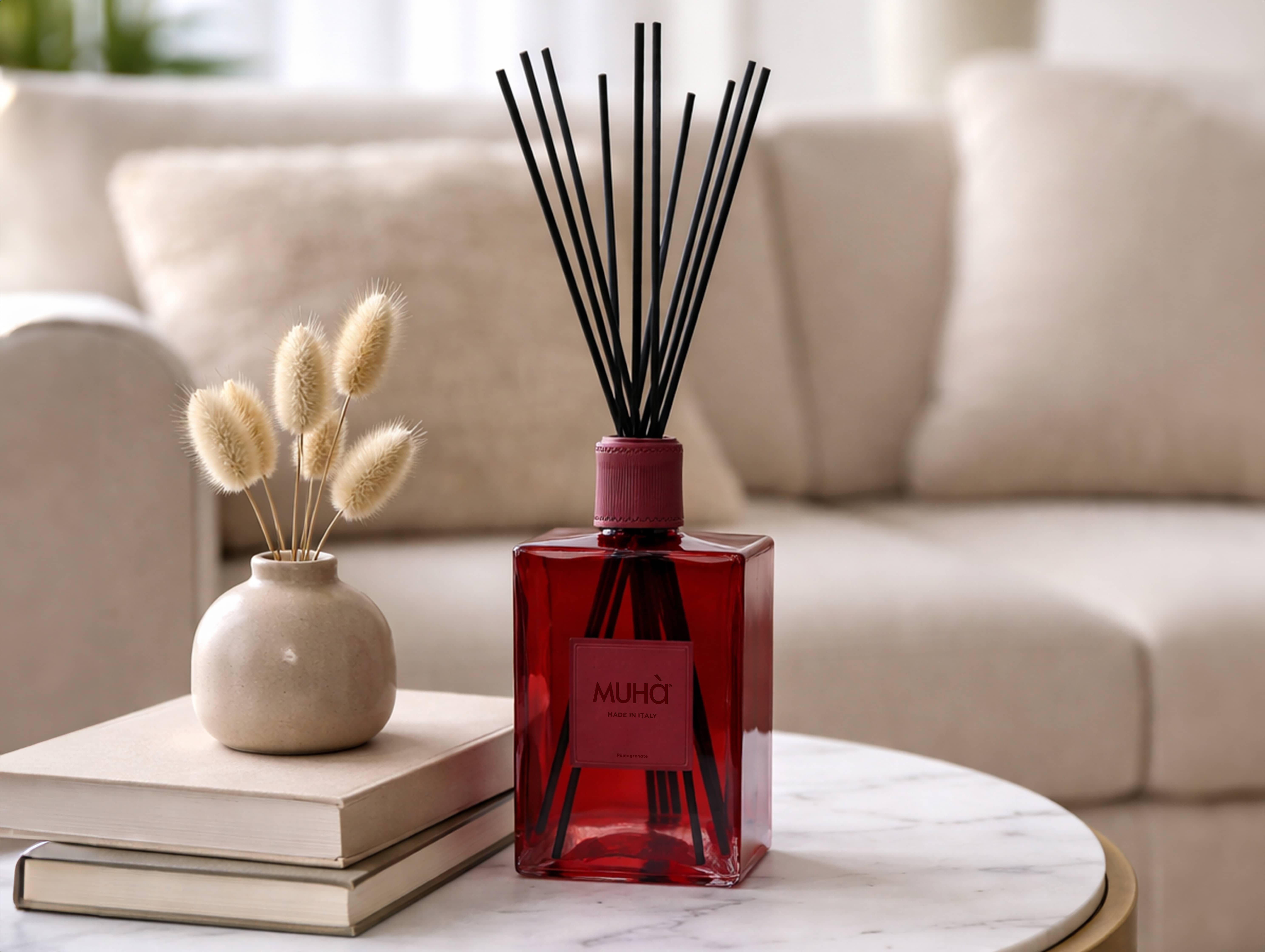 Red glass reed diffuser styled on a coffee table in a calm living room setting.