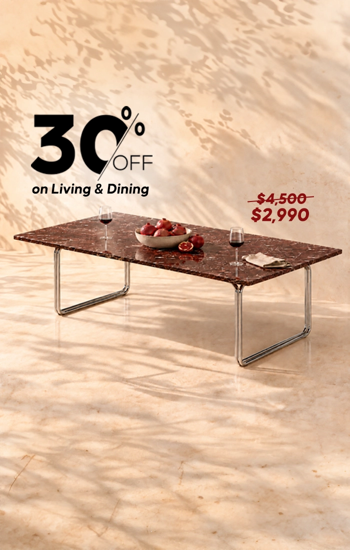 Rectangular dark marble dining table with sleek chrome legs, styled with fruit, wine glasses, and tableware against a warm beige background.