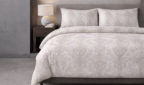 Neutral bedding set with layered pillows creating a calm and cozy bedroom atmosphere.