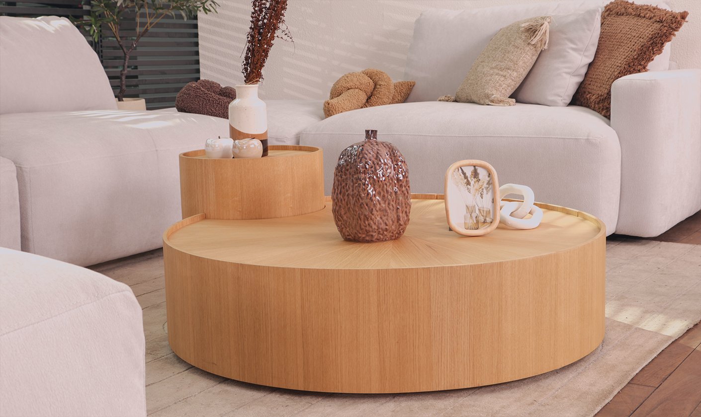 Round wooden side table styled with decorative vases in a contemporary living room.